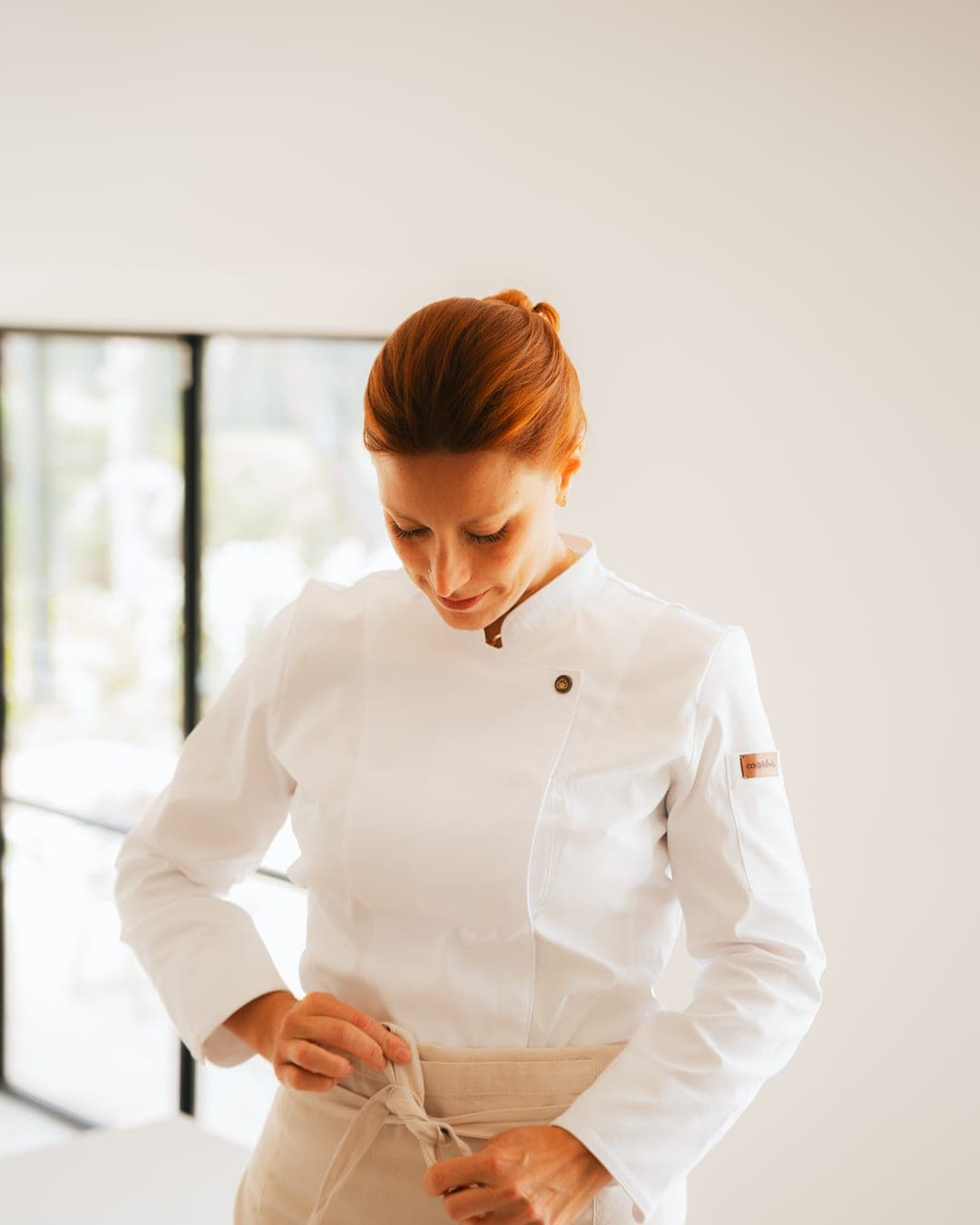 Chef Lara Petrella tying her apron in a bright Costa Brava villa kitchen