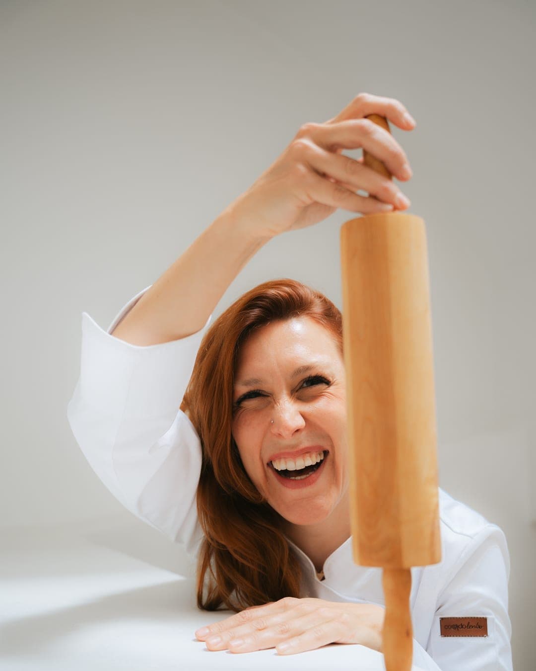 Chef Lara Petrella laughing while holding a wooden rolling pin