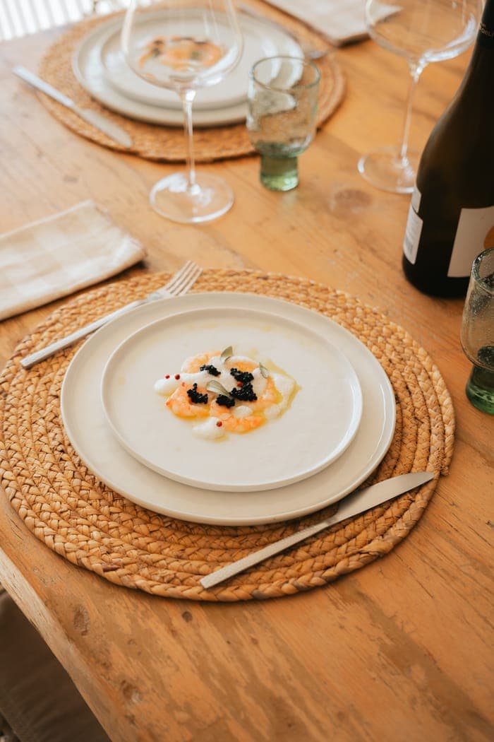 A plated prawn and caviar starter at a fully set dinner table