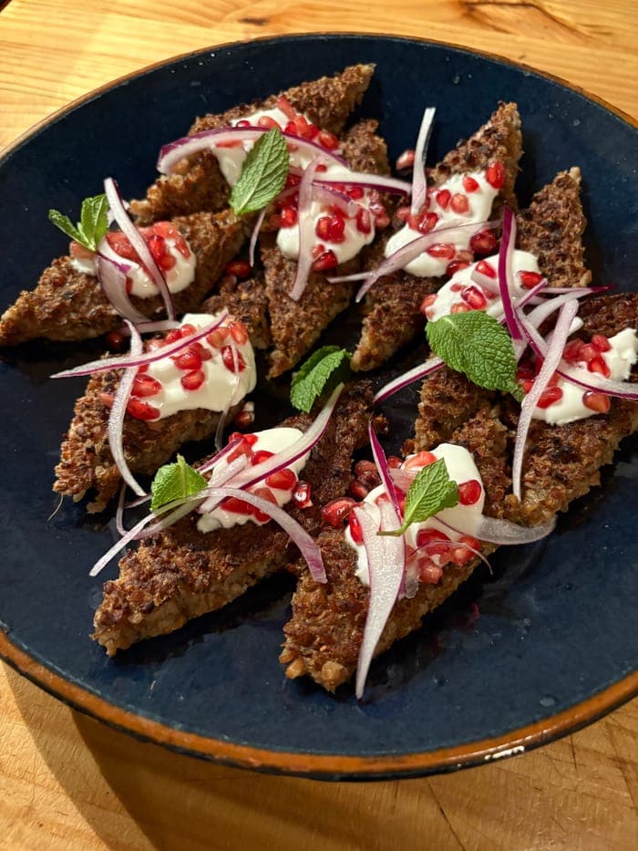 Crispy grain crackers topped with pomegranate, yoghurt and red onion