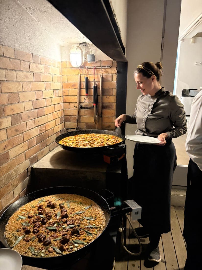 Chef Lara Petrella serving paella from two large pans