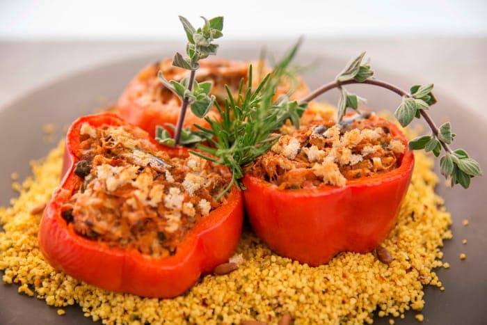 Stuffed red peppers on a bed of golden couscous